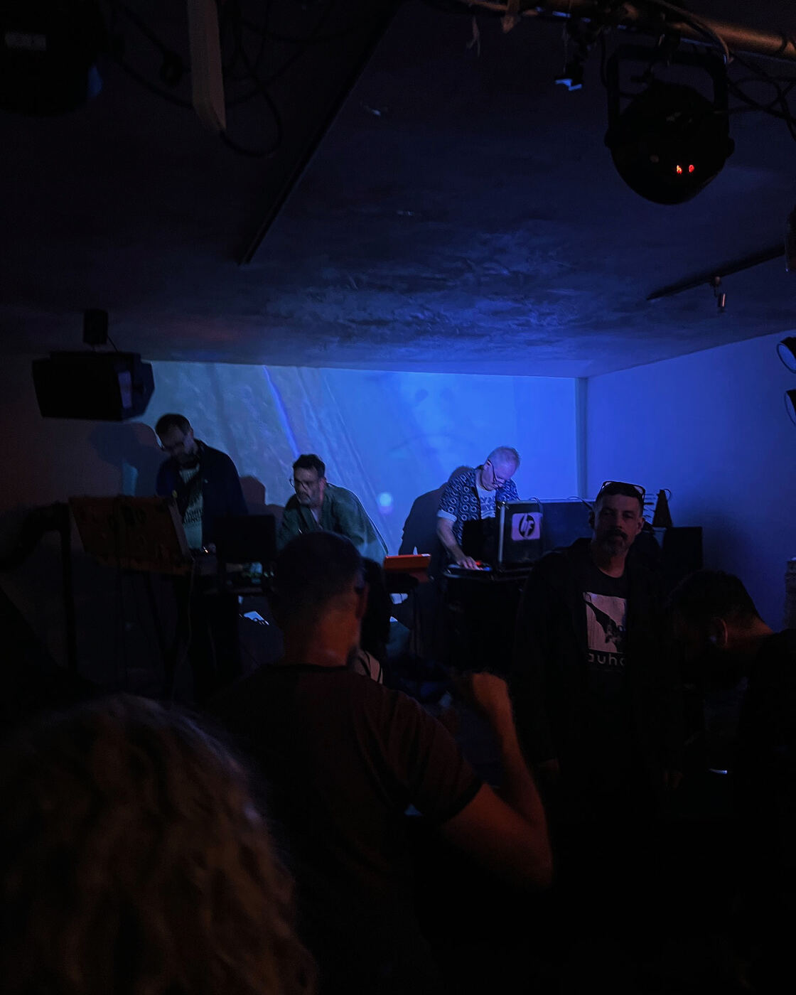 REEL performing live under blue stage lighting, seen from the crowd