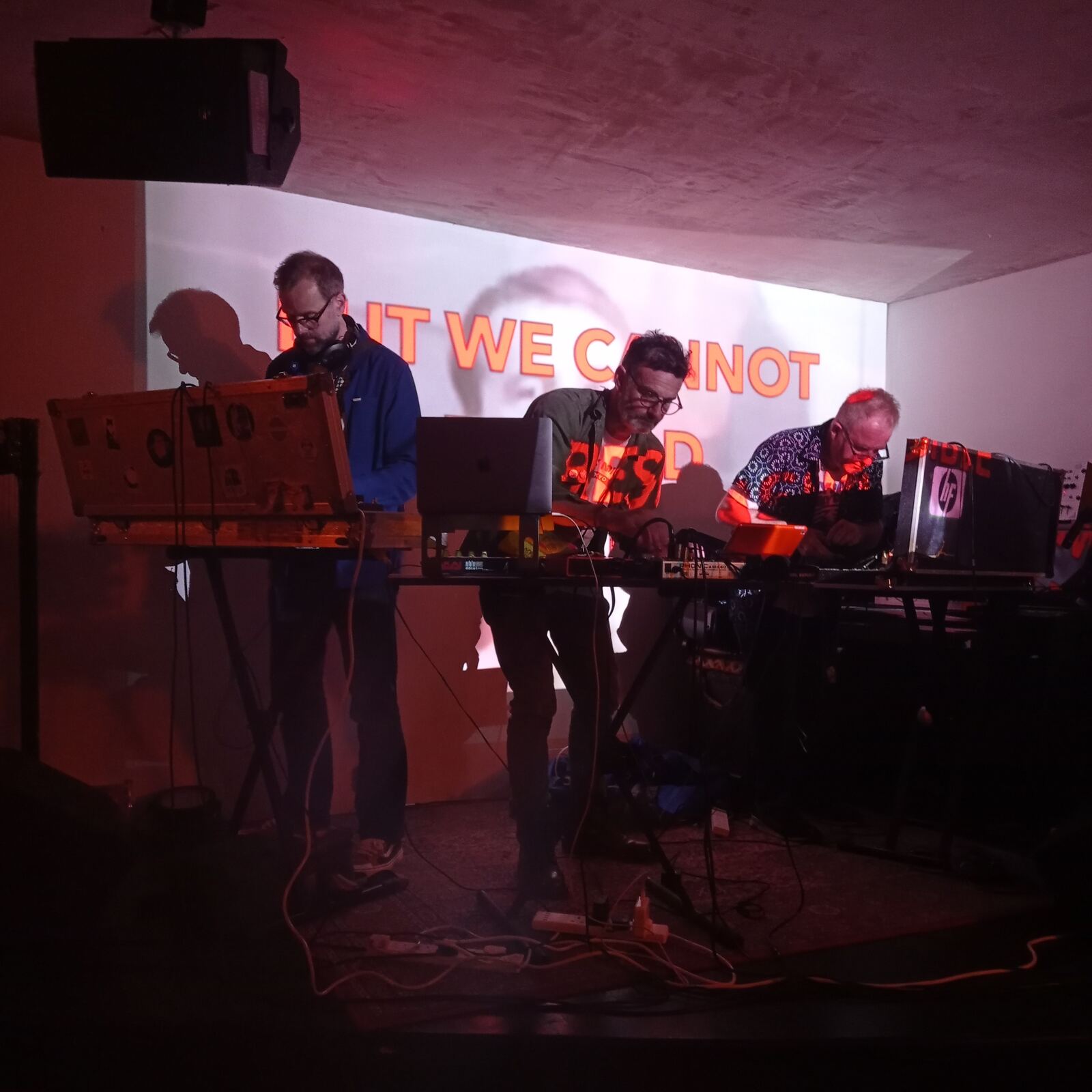 REEL performing live with projected text reading BUT WE CANNOT