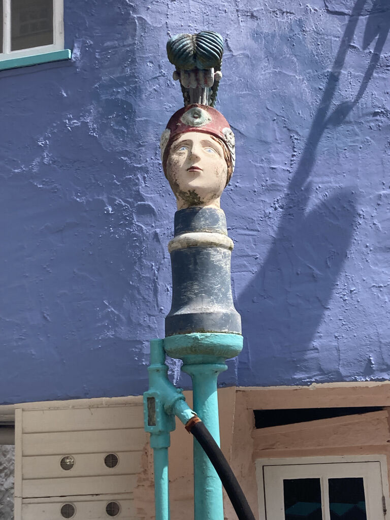Painted finial head mounted on a pipe against a blue wall